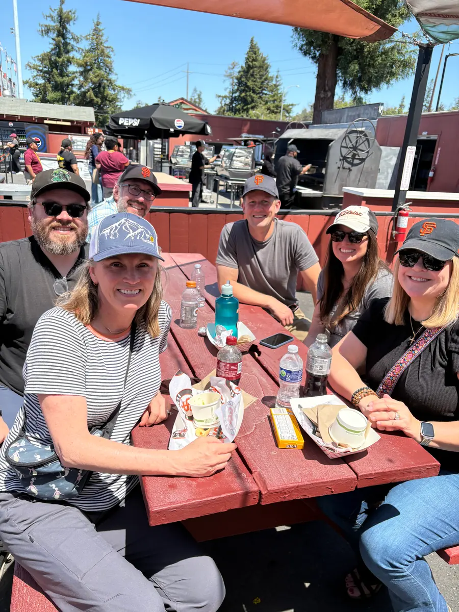 PCLG friends gathered around a picnic table during a baseball outing.