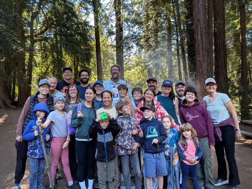 Parents, children, and teenagers from the church standing together among the redwoods.