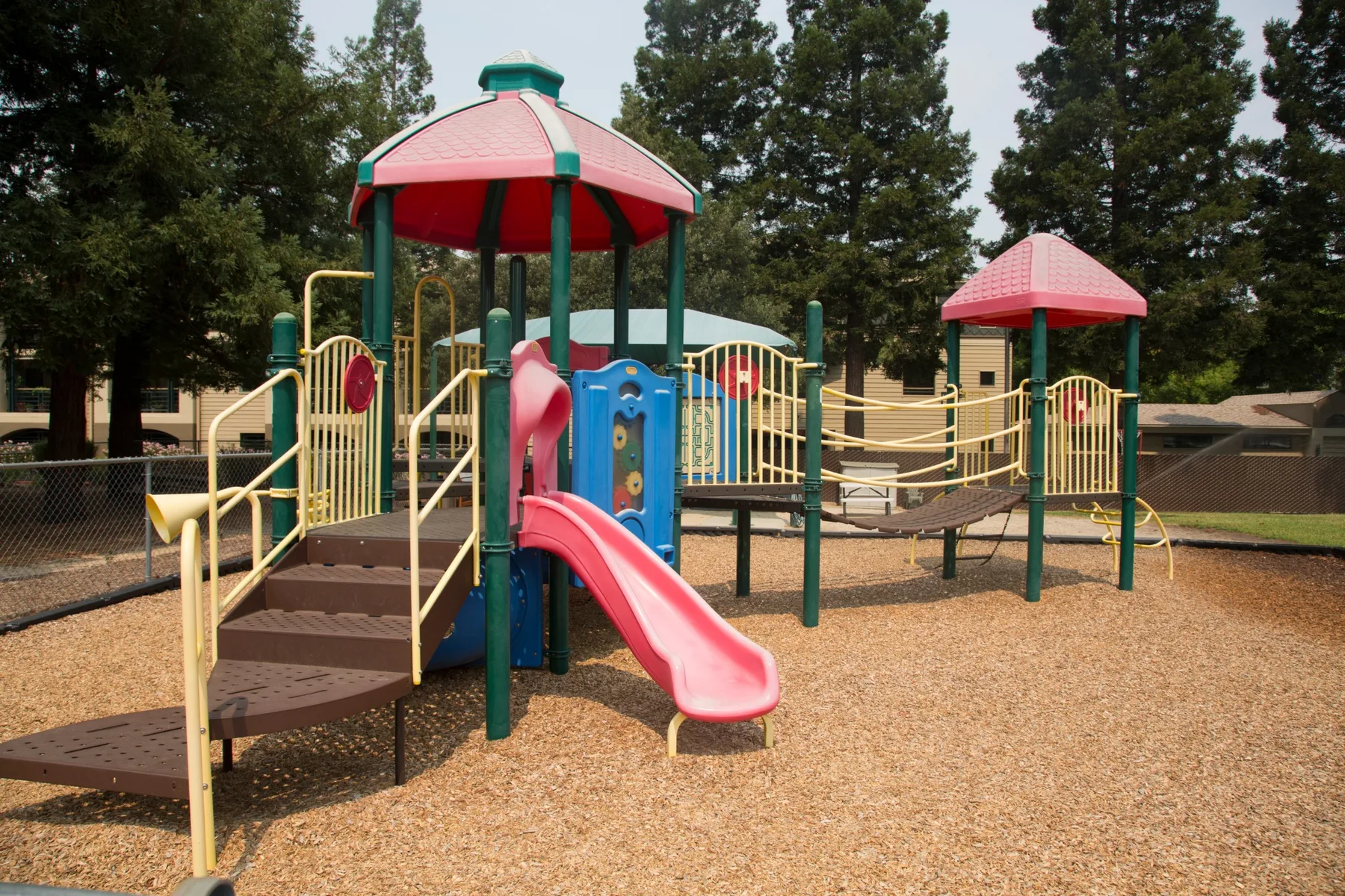 The Growing FootPrints play structure and slides beneath the redwoods on the PCLG campus.