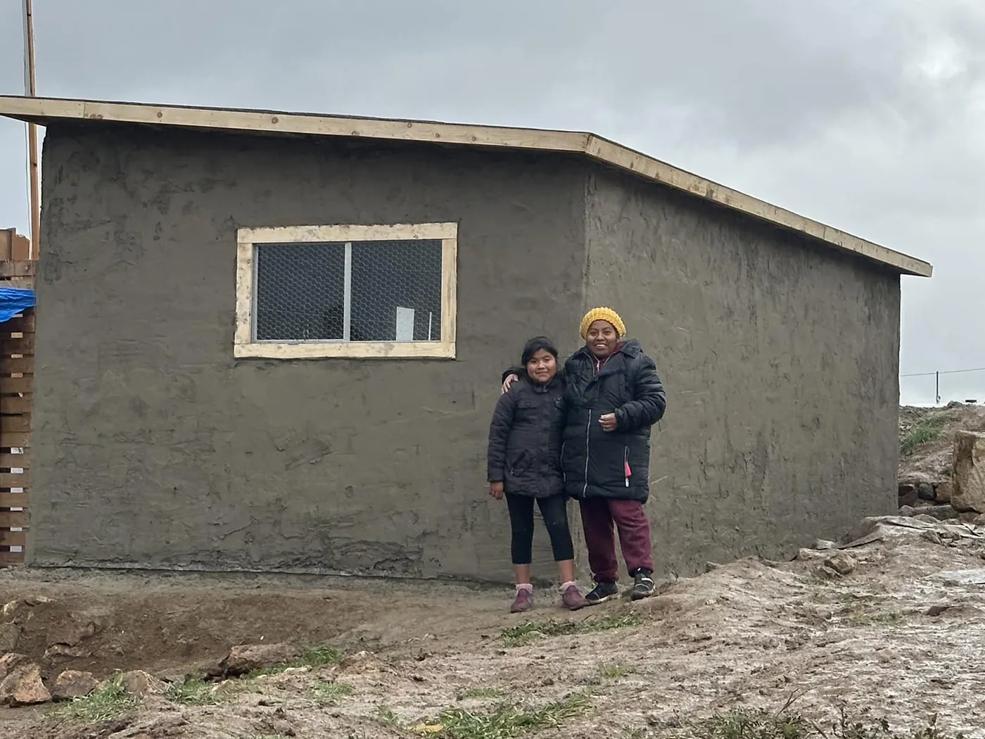 A mother and daughter standing outside the finished house the all-church team built with them.
