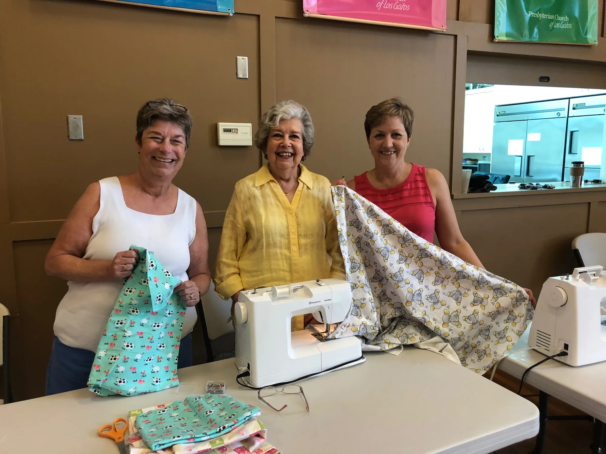 Three Sophia's Layette volunteers sewing baby blankets together in our fellowship space.