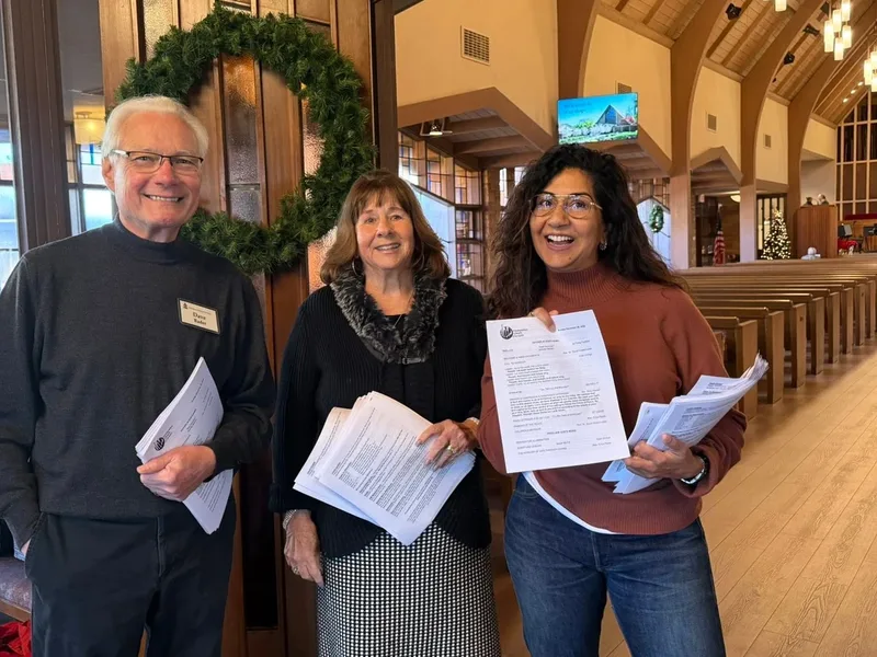 Three PCLG ushers with armfuls of Sunday bulletins at the Sanctuary doors.