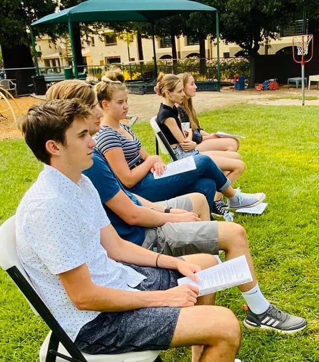 PCLG students seated outside on the lawn, reading together