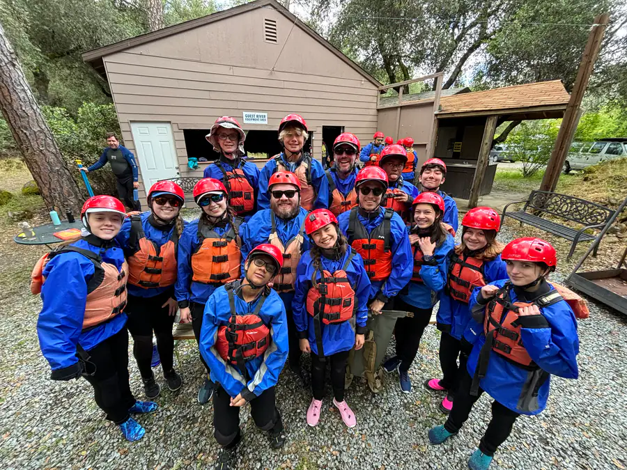 PCLG youth and adult leaders wearing helmets and life jackets before a whitewater trip.